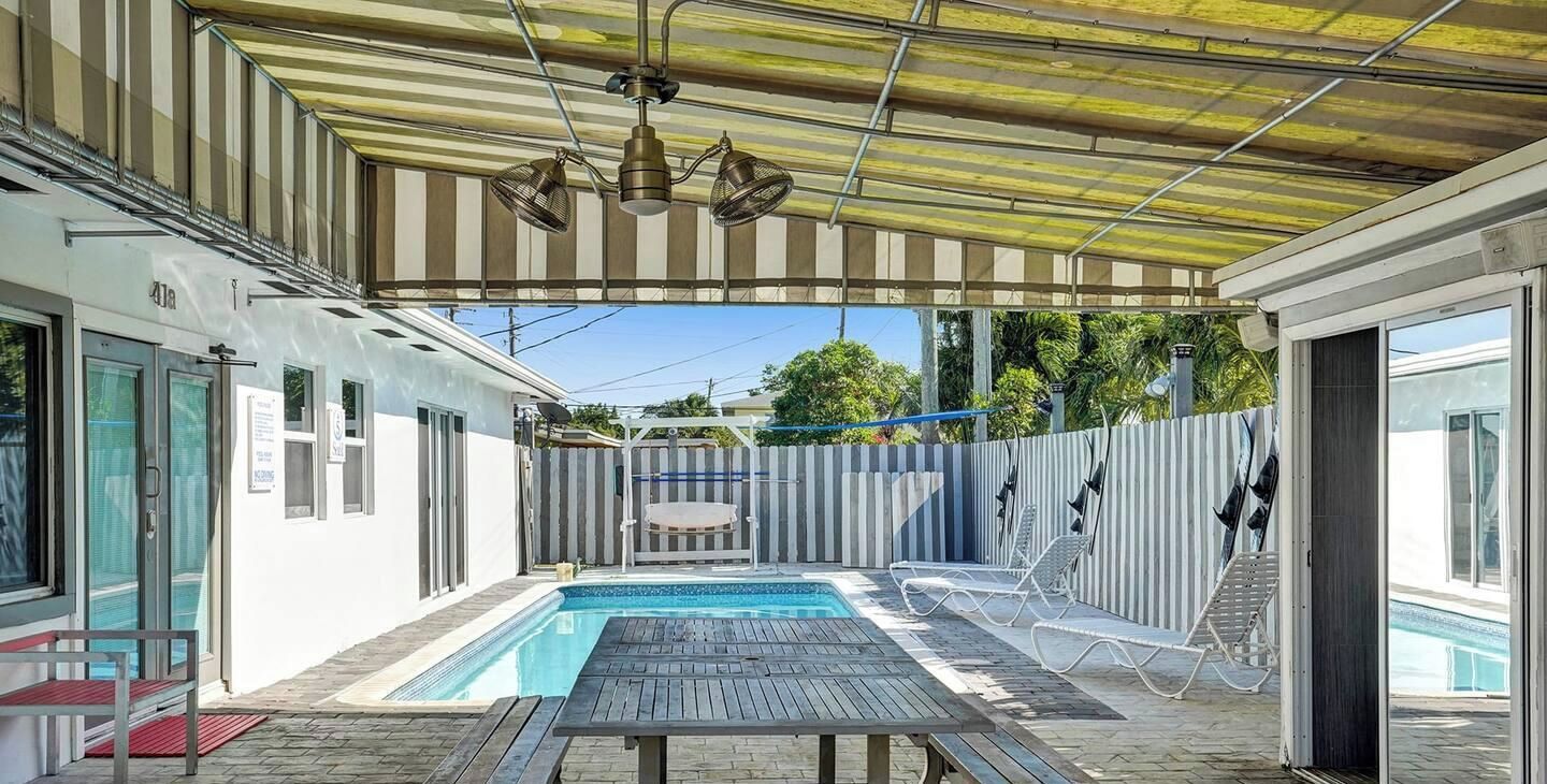 Un espace extérieur abrité avec une piscine, une table et des chaises longues.