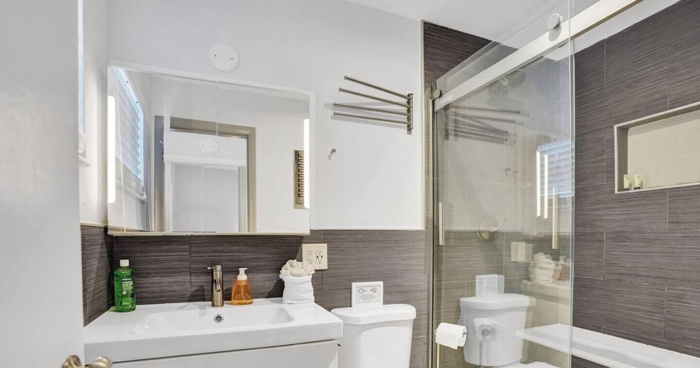 Une salle de bain moderne avec une douche à parois de verre, un lavabo blanc et des toilettes.