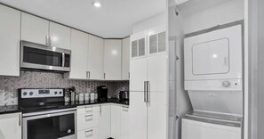 Una cocina moderna con armarios blancos, microondas, estufa y horno empotrado.