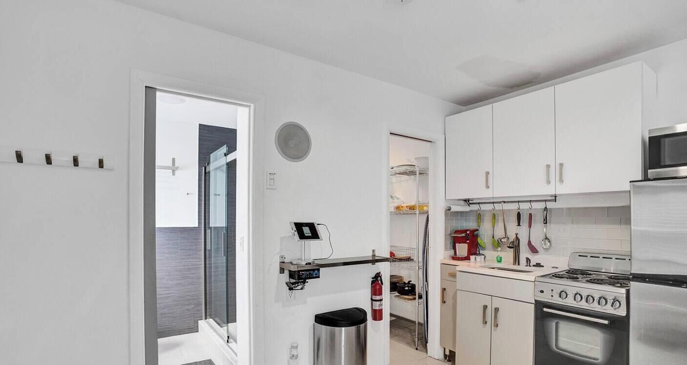 Una cocina moderna con armarios blancos, estufa de acero inoxidable y microondas.