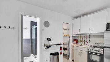 Una cocina moderna con armarios blancos, estufa de acero inoxidable y microondas.