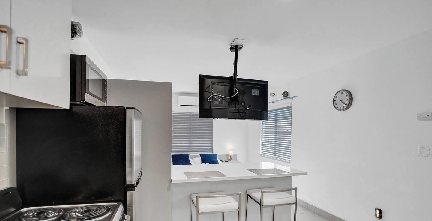 Una cucina moderna con un fornello, un forno a microonde e un piccolo bancone con sgabelli.