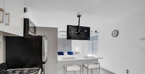 Une cuisine moderne équipée d’une cuisinière, d’un four à micro-ondes et d’un petit coin bar avec des tabourets.