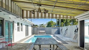 A covered outdoor area with a pool, a table, and lounge chairs. - Private unit w/pool view & patio (Deerfield Beach)
