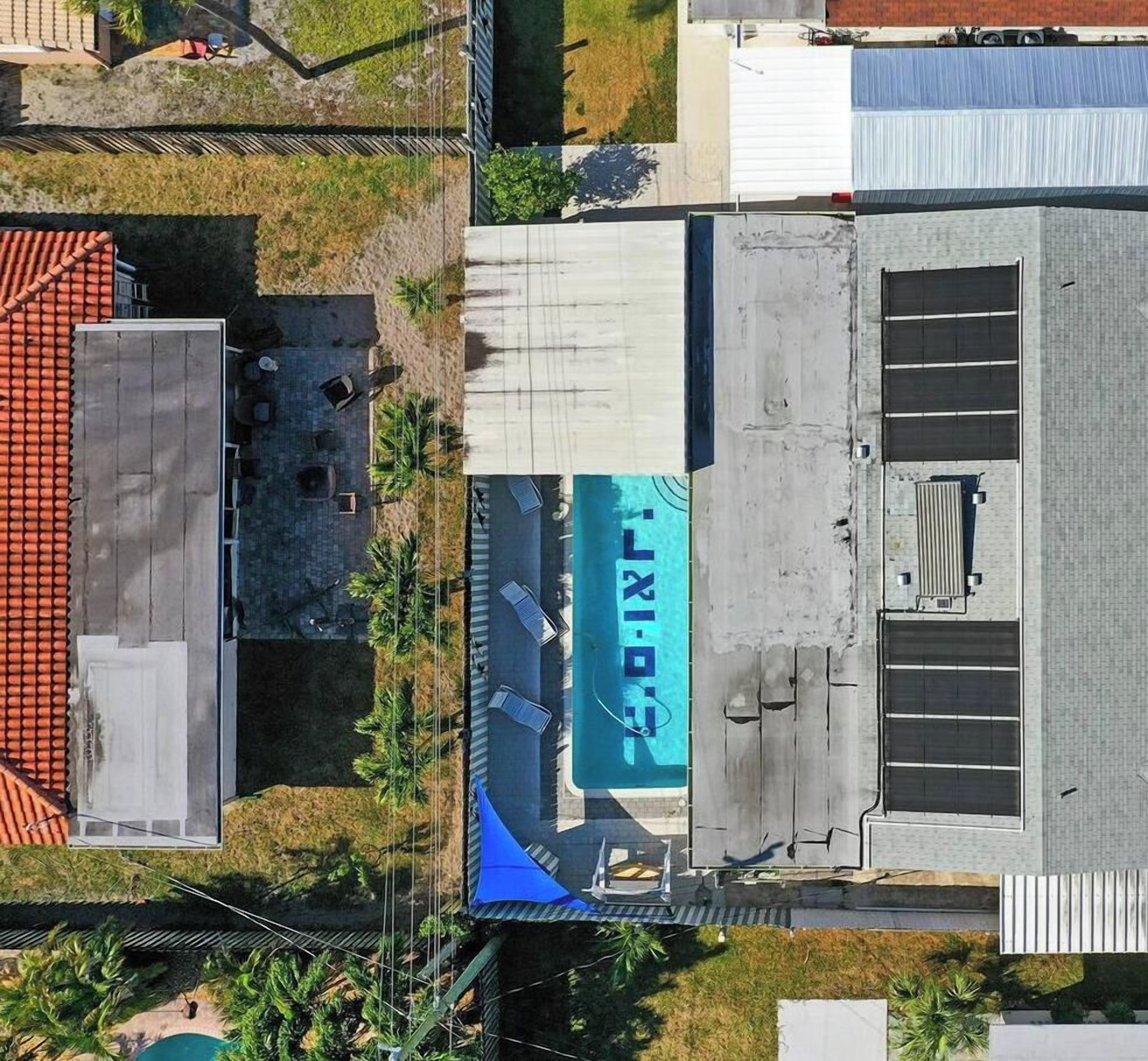 Una vista aerea di un edificio con tetto piatto, un grande cartello con la scritta 'LIXI' e un'area recintata con un piccolo prato.