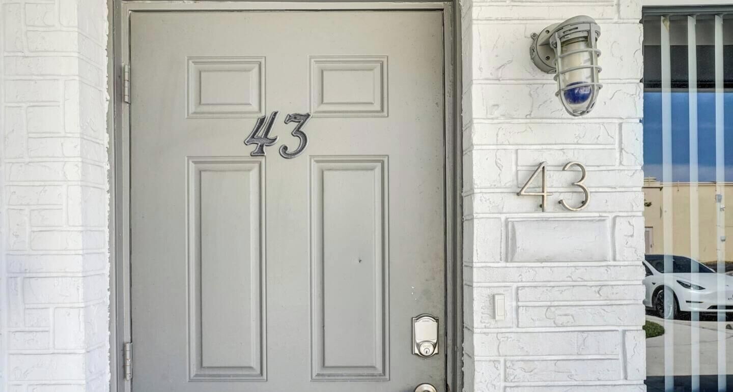 Una puerta blanca con el número 43, un buzón y una lámpara en la pared.