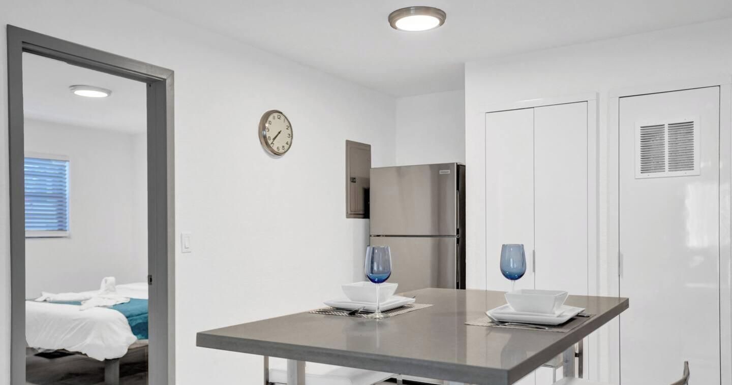 Et moderne køkken med et rustfrit stål køleskab, et ur på væggen og et spisebord med blåt glas.