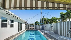 Une piscine dotée d’une zone abritée, d’un poste de surveillance pour les sauveteurs et d’un panneau indiquant les règles de la piscine.
