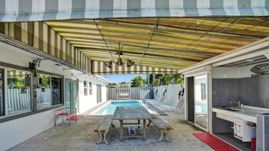 Un espace extérieur abrité comprenant une piscine, une table et un coin cuisine.