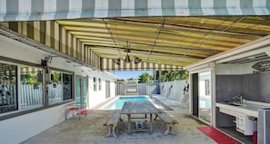 Un espace extérieur abrité comprenant une piscine, une table et un coin cuisine.