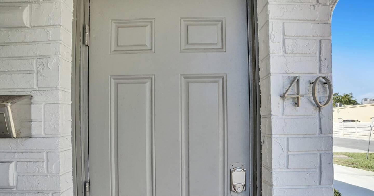 A white door with a rectangular panel design, a doorbell, and a mailbox on the left. The number '40' is visible on the right side of the door.