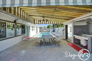 Área externa coberta com piscina, mesa e espaço para cozinha.