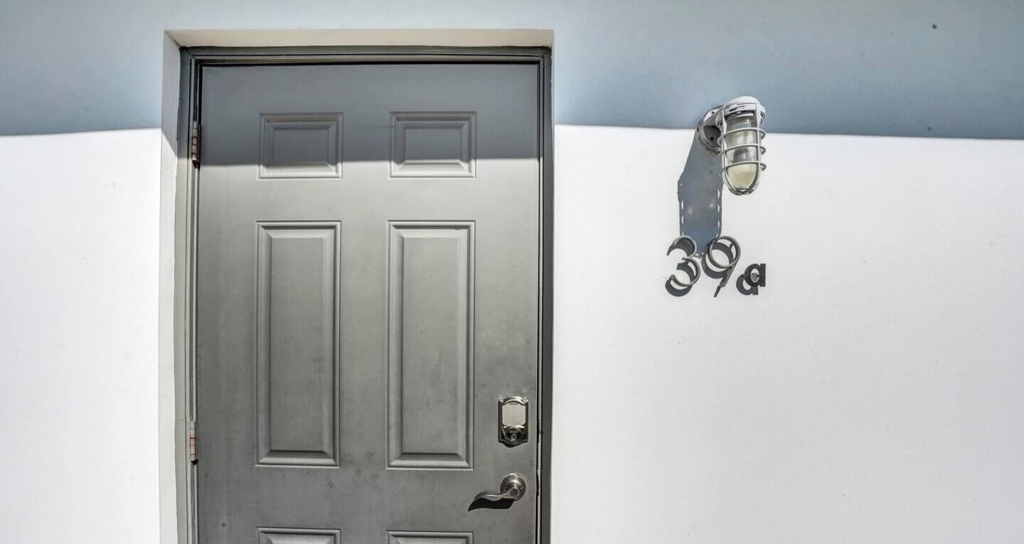 Una porta metallica con una serratura e una maniglia, e un lampadario a parete.
