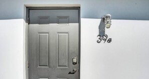 Una porta metallica con una serratura e una maniglia, e un lampadario a parete.