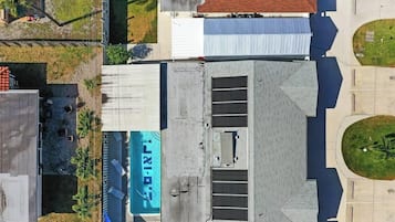 Vista aérea de um edifício com telhado plano, um grande letreiro com 'LIXI' e uma área cercada com um pequeno gramado.