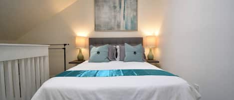 Un dormitorio con una cama, dos lámparas de noche, un cuadro en la pared y una ventana con persianas.