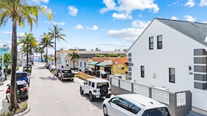 A street lined with parked cars and palm trees, with buildings featuring a mix of modern and traditional architecture. - Modern Loft w/Queen Loft & Steps to Beach (Hollywood)