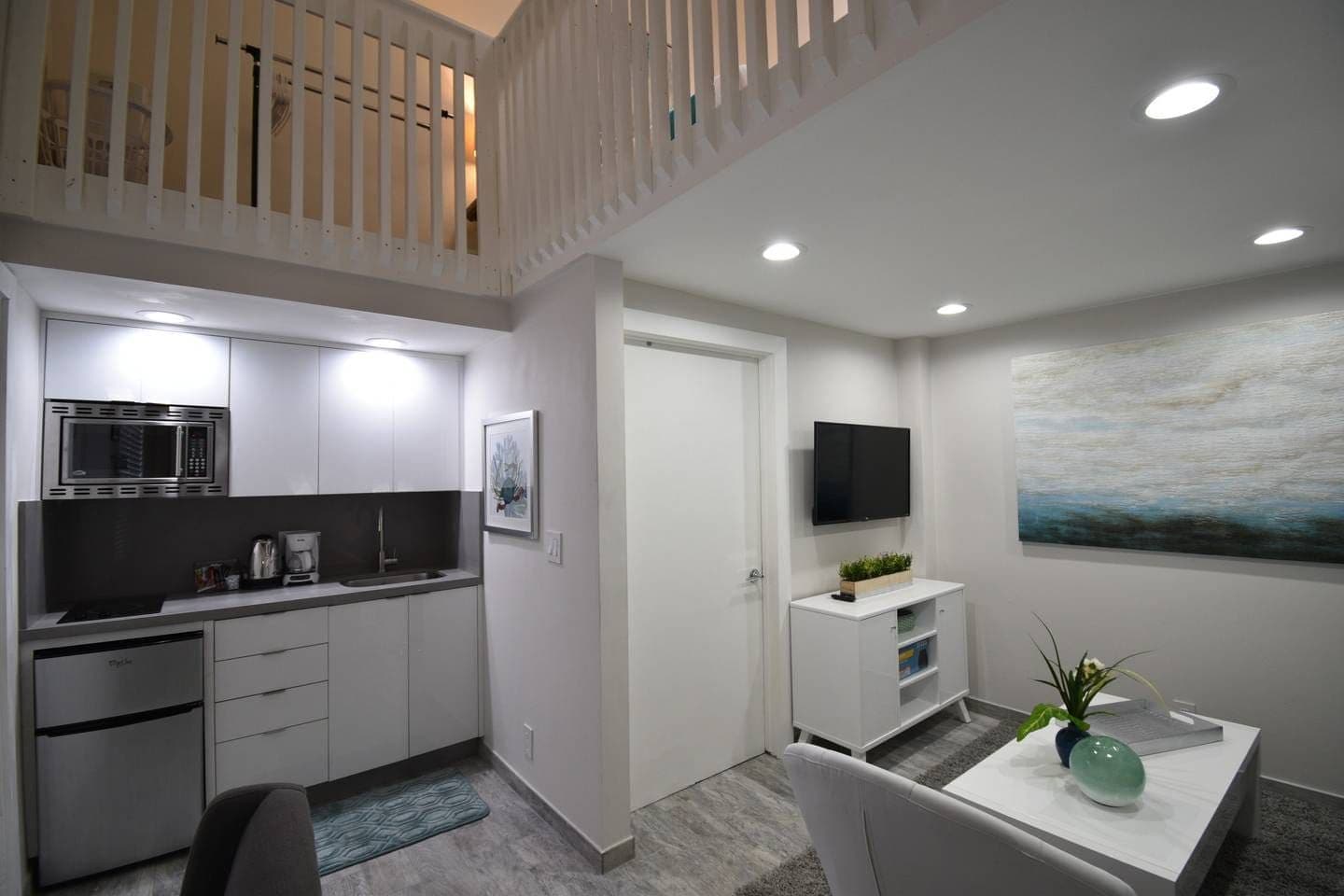 A modern kitchen with a microwave, coffee maker, and a dining area with a table and chairs.
