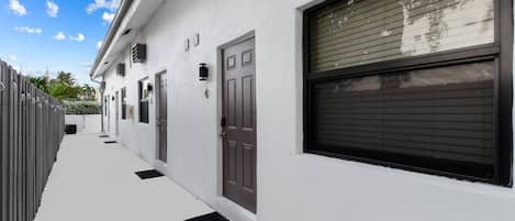 A modern building with a white facade, multiple garage doors, and a clear sky.