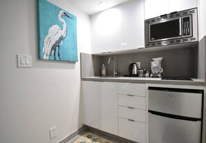 A modern kitchen with white cabinets, a stainless steel refrigerator, a microwave, a coffee maker, and a sink. - Lofted Apt w/Queen Loft & Nook steps to Beach (Hollywood)