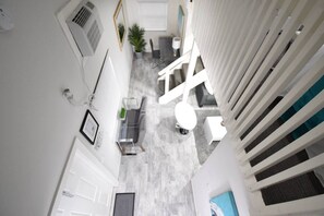 A narrow corridor with a seating area, a white door, and a staircase. - Lofted Apt w/Queen Loft & Nook steps to Beach (Hollywood)