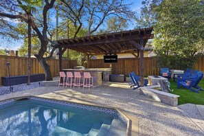 A backyard with a swimming pool, a barbecue area, and outdoor seating.