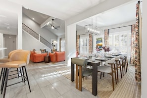 A spacious dining area with a high ceiling, a staircase, and a view of the outdoors.