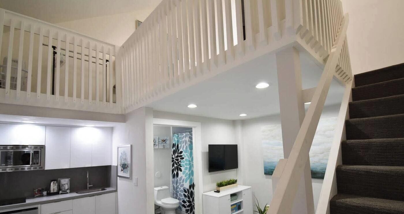 A modern interior with a kitchen, a bathroom with a shower, and a staircase.