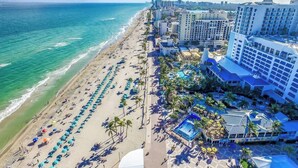 Un hotel sulla spiaggia con più livelli, una piscina e una spiaggia con ombrelloni.