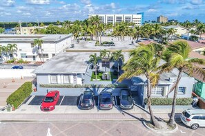 A parking lot with several cars, a building with a flat roof, and palm trees. - Modern studio w/queen bed & beach views (Hollywood)