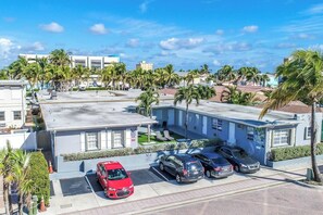 A multi-story hotel with a parking lot, palm trees, and a clear blue sky. - Modern studio w/queen bed & beach views (Hollywood)