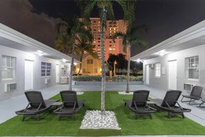 A courtyard with outdoor seating and a view of a tall building at night. - Modern studio w/queen bed & beach views (Hollywood)