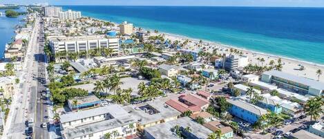 An aerial view of a coastal city with a beachfront, buildings, and roads.