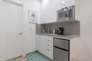A compact kitchen with a microwave, coffee maker, and a refrigerator. - Renovated studio w/ ocean views & boardwalk steps (Hollywood)