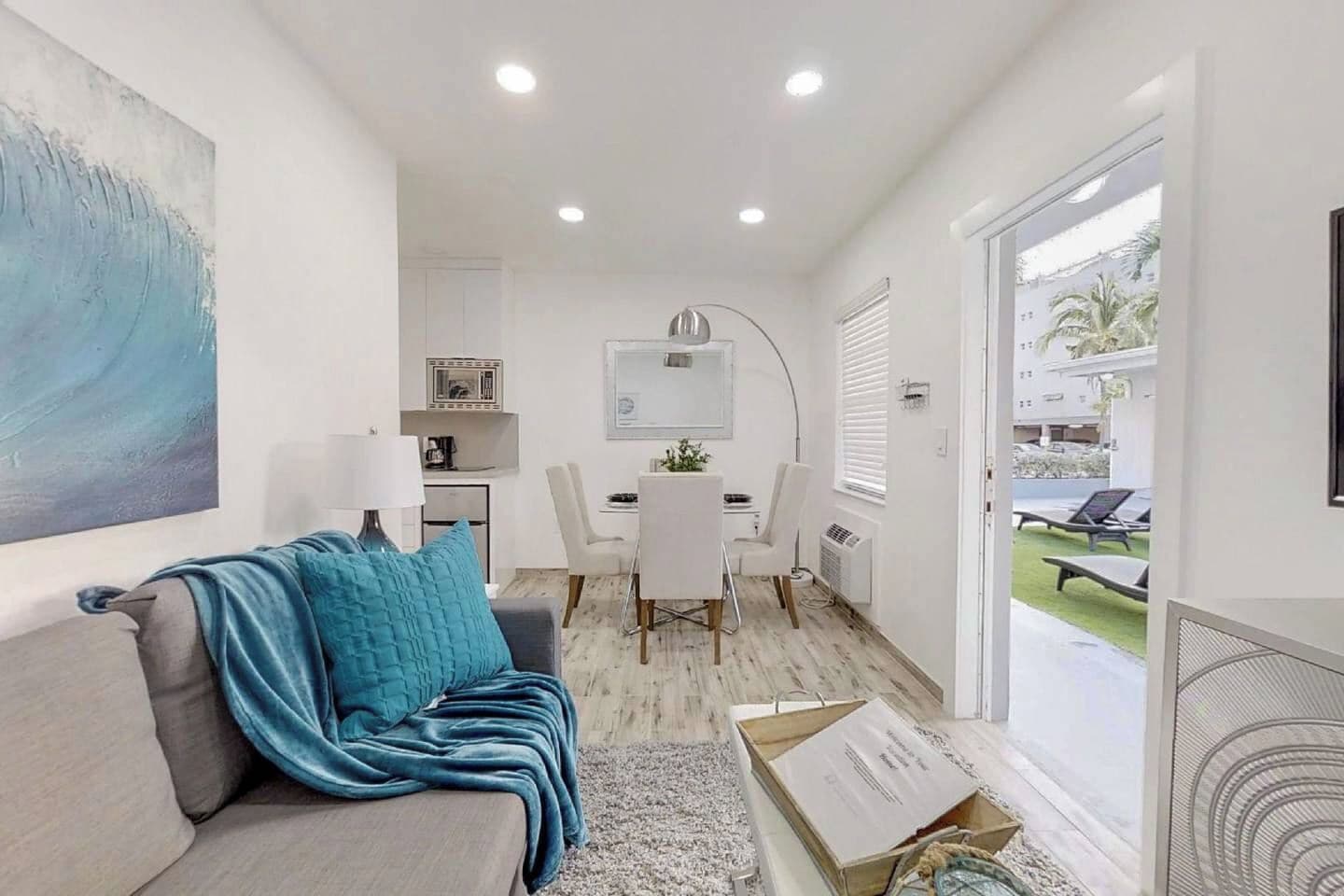 A modern living room with a sofa, a dining table, and a kitchen area in the background.