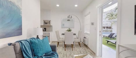 Una sala moderna con un sofá, una mesa de comedor y una cocina al fondo.