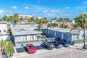 A multi-story hotel with a parking lot, palm trees, and a clear blue sky. - Modern apartment w/king bed & steps to beach (Hollywood)