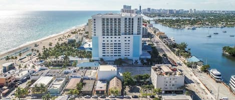 Ein Hotel an der Küste mit einem zentralen Gebäude, direkt am Strand und einem Yachthafen.