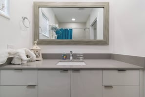 Une salle de bain avec un grand miroir, un lavabo et un porte-serviettes.
