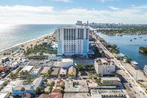 Un hôtel situé sur la côte, avec un bâtiment principal, un accès direct à la plage et un port de plaisance.