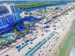 Une station balnéaire dotée d’une grande piscine, de parasols de plage et d’un hôtel à plusieurs étages.