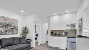 Cocina moderna con armarios blancos, microondas y refrigerador.