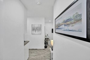Ein Flur mit Holzboden, weißen Wänden und zwei gerahmten Kunstwerken.