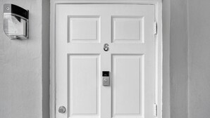 Una puerta blanca con un ojo de cerradura y un timbre.