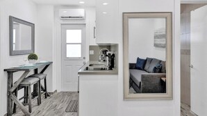 Un apartamento moderno con comedor, kitchenette y sala de estar con sofá y un espejo grande.