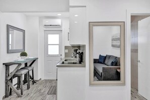 A modern apartment with a dining area, kitchenette, and a living space with a sofa and a large mirror. - Spacious 2BR condo w/ beach access (Hollywood)