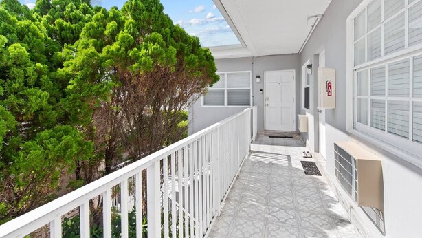 A balcony with a white railing, a door, and a fire alarm. - Cozy 2BR aparthotel near hollywood boardwalk (Hollywood)