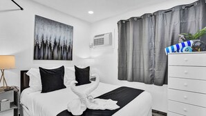 A hotel room with a bed, a white dresser, a painting on the wall, and a window with curtains. - Cozy 2BR aparthotel near hollywood boardwalk (Hollywood)