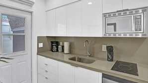 A modern kitchen with white cabinets, a stainless steel sink, a microwave, and a built-in induction cooktop. - Cozy 2BR aparthotel near hollywood boardwalk (Hollywood)