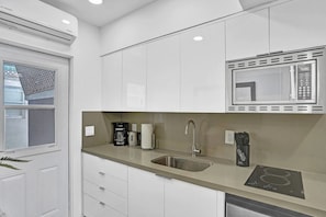 Eine moderne Küche mit weißen Schränken, einer Edelstahlspüle, einer Mikrowelle und einem integrierten Induktionskochfeld.
